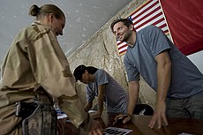 Cooper (à direita) assina autógrafos para militares da Base Aérea de Bagram, Afeganistão, em 14 de julho de 2009.