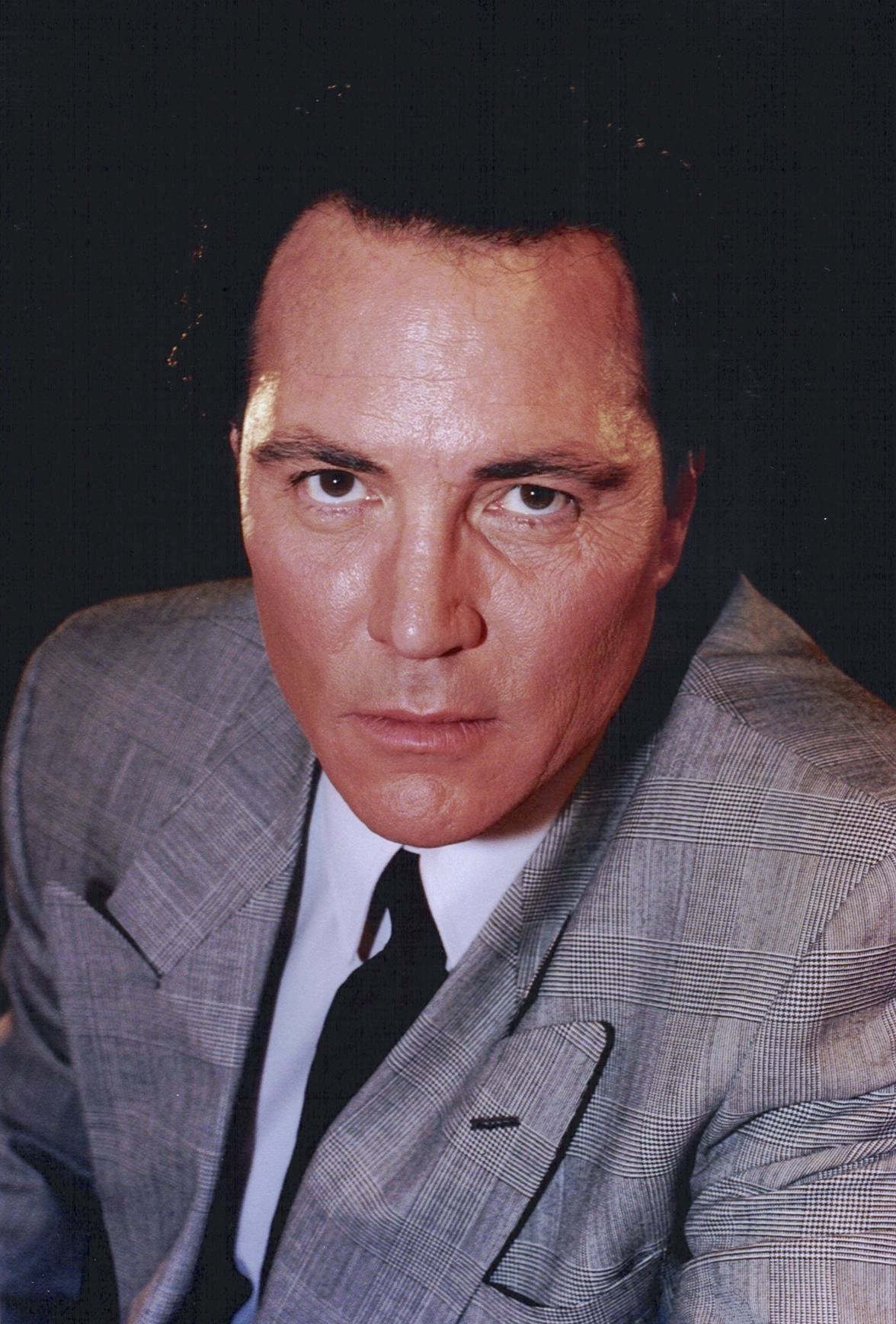 Ator Sonny Landham de terno sério na foto Imagoi